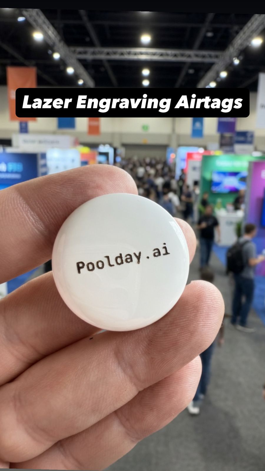 Laser engraved round white token held up in front of a busy event floor